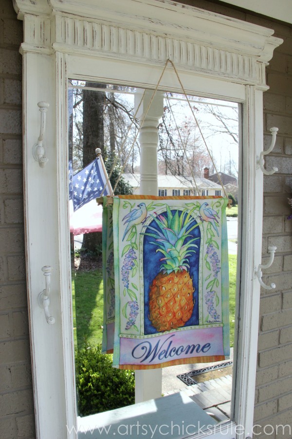 hall tree with welcome flag hanging over mirror