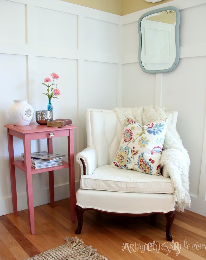 white chair in corner with coral colored side table