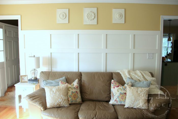 wall medallions hanging on yellow wall with tan leather couch below