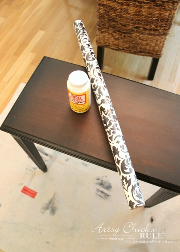 black table with roll of wrapping paper and mod podge