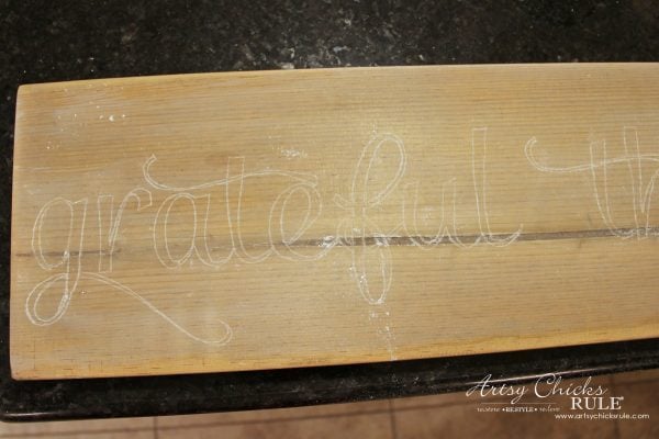 dark wood board with white letter traced
