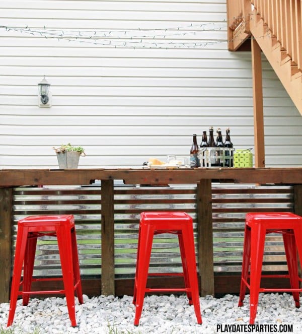 An outdoor pallet bar with red stools.
