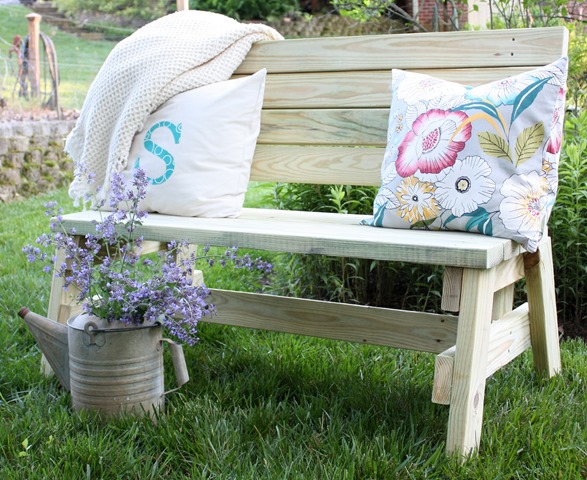 A wooden bench with brightly coloured pillows.