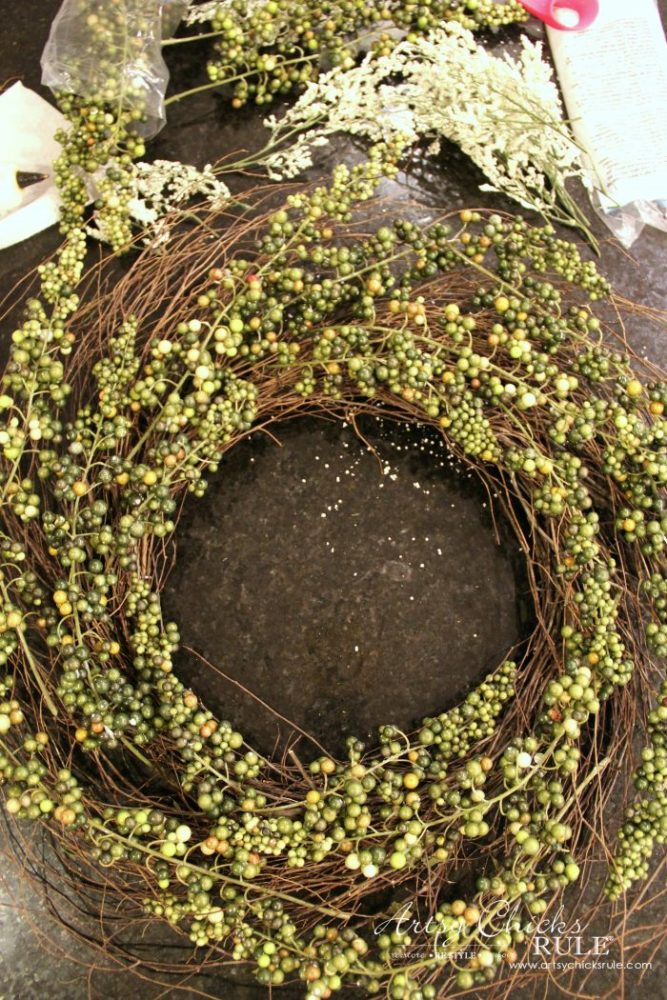 Adding the green berry sprigs to the wreath