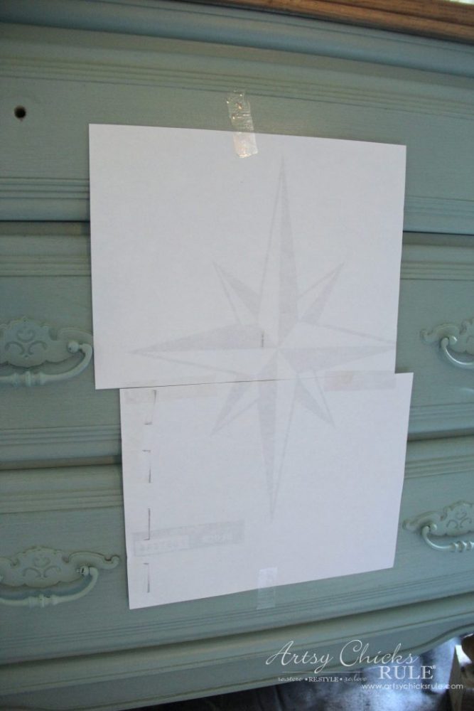 paper with design taped to front of painted dresser