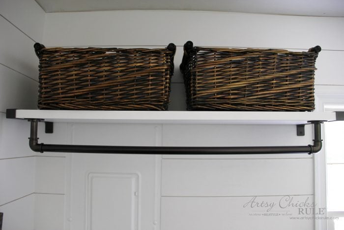 white shelf with bronze clothes rod and baskets