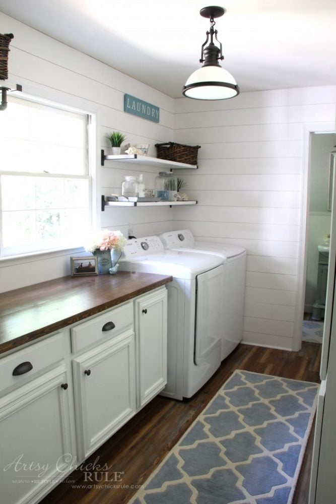 bright and light laundry room with white shiplap, white cabinets and blue rug