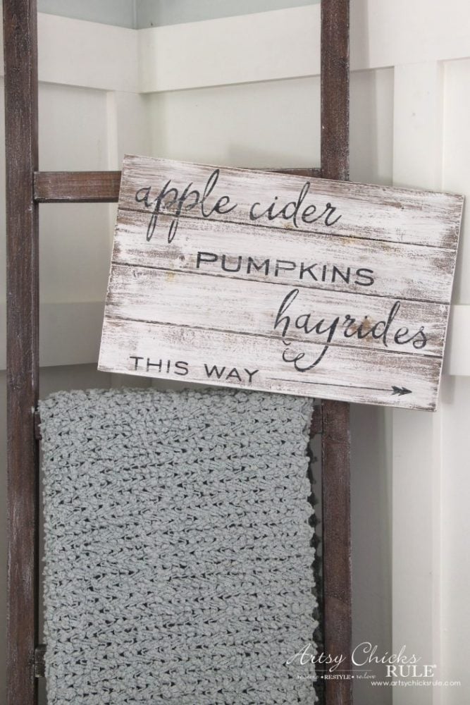 whitewashed sign hanging on ladder with apple cider saying