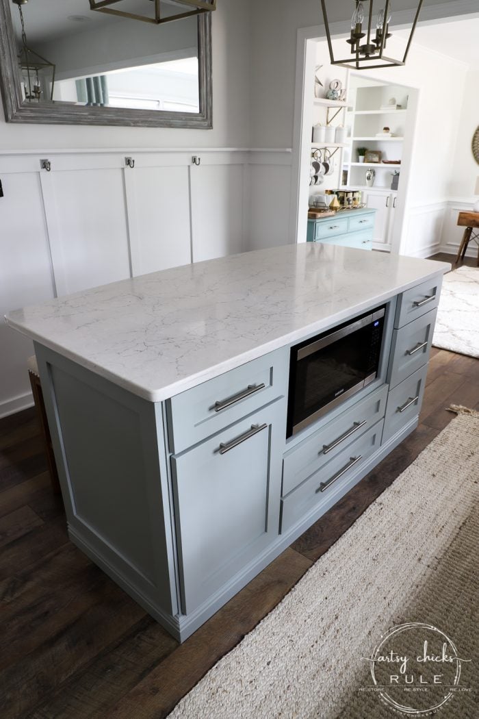 kitchen with blue island white quartz top and wood and white wall treatment 