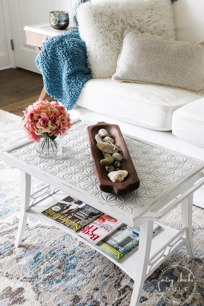 white table with tiled top and white couch living room