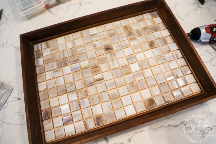 Thrift Store Makeover with TILE!! Simple makeover using an old, framed print. Just add hardware and cute little feet! artsychicksrule.com #tiledtray #tileprojects #thriftstoremakeover #thriftydecor