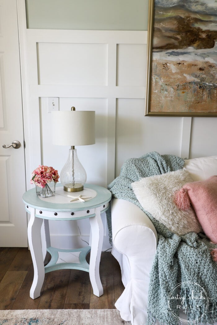 white and light blue table with dark rivets beside couch