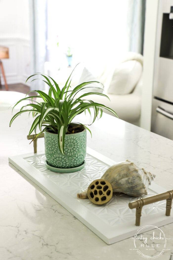 white tray with gold handles and white tiles on counter with green plant