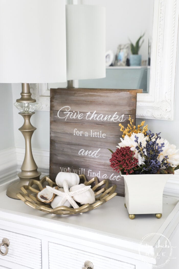 white foyer table with mirror and white dish with colorful fall floral