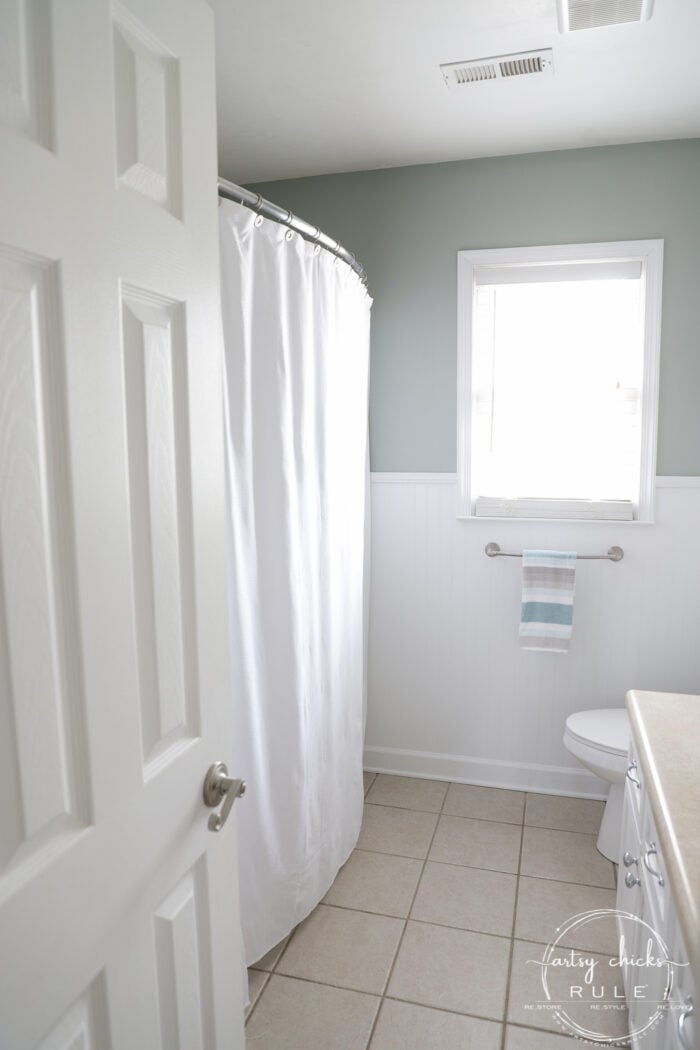 white shower curtain, blue walls tan square tile floor