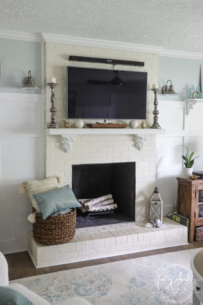 TV over white mantel on creamy brick painted fireplace