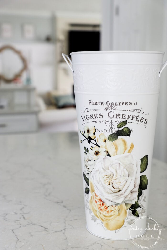 tall white metal vase with yellow and white flowers on front