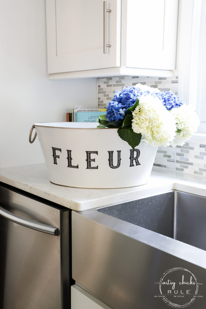 white bucket with purple and white flowers on sink