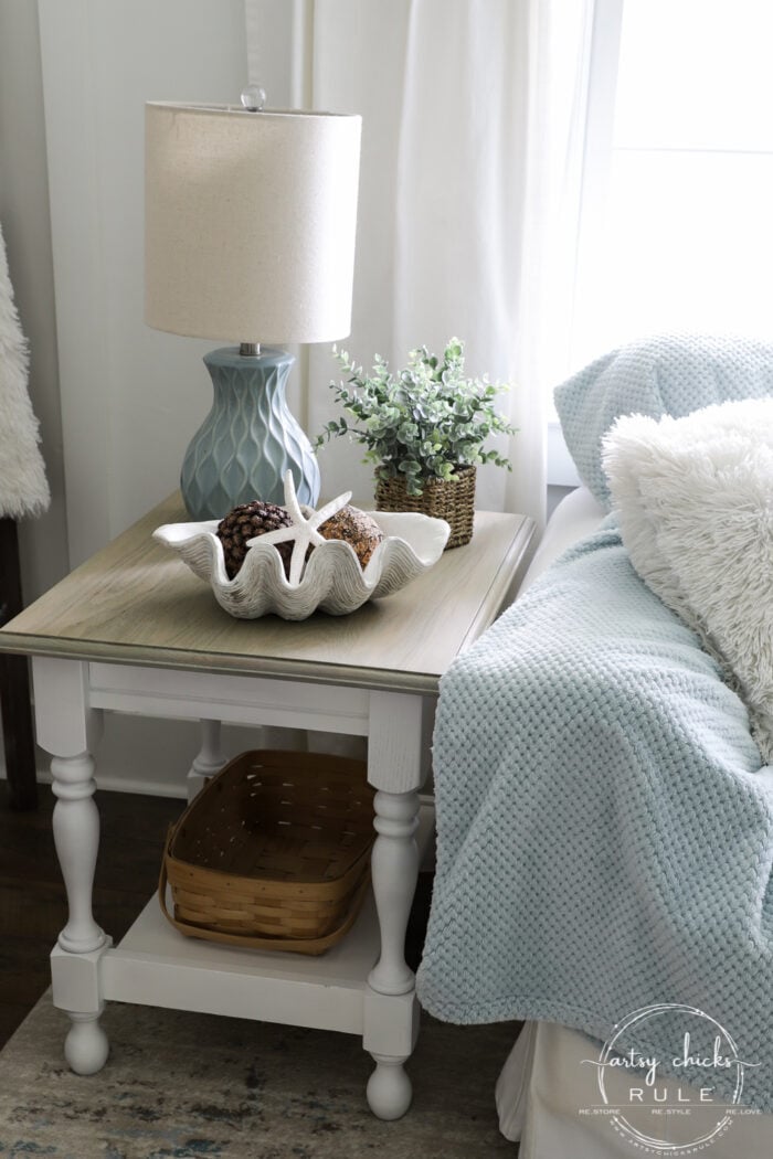 finished side table with blue lamp beside blue blanket on couch