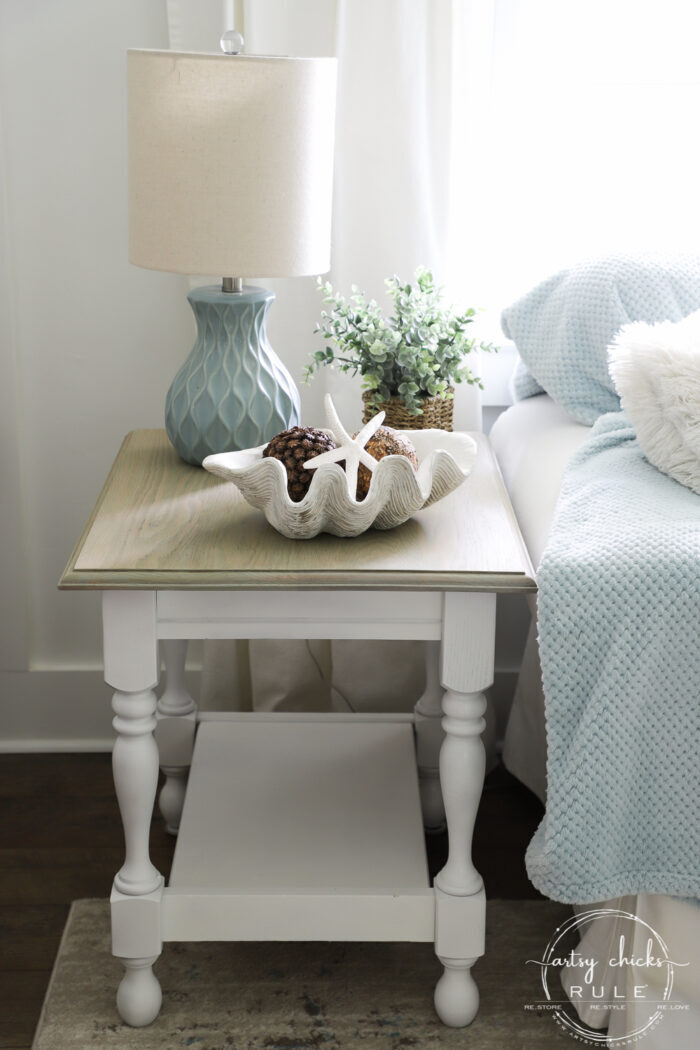 side table with bleached top and white base beside white couch