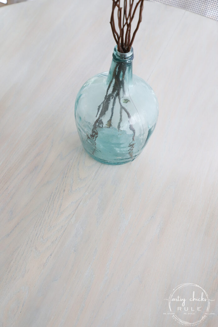 light colored wood table top with aqua glass vase