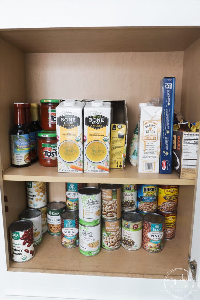 cabinet with cans of beans, chicken broth and salsa