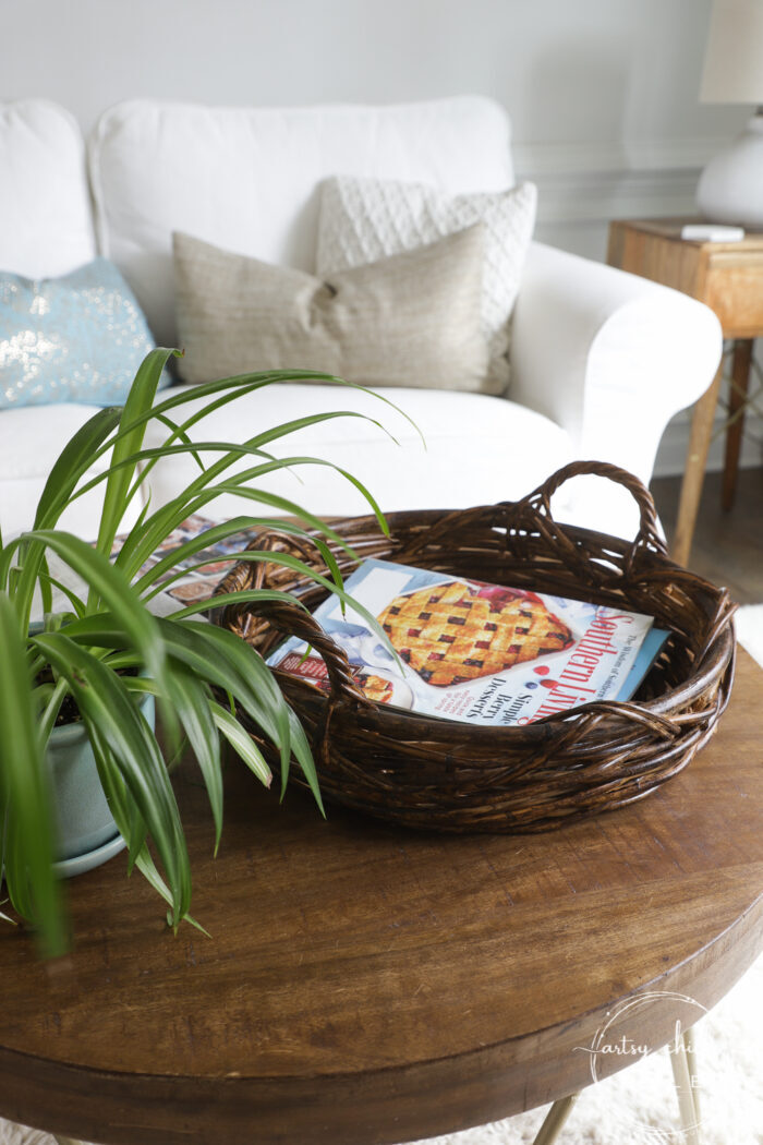 Dark stained round basket on small round coffee table with magazines