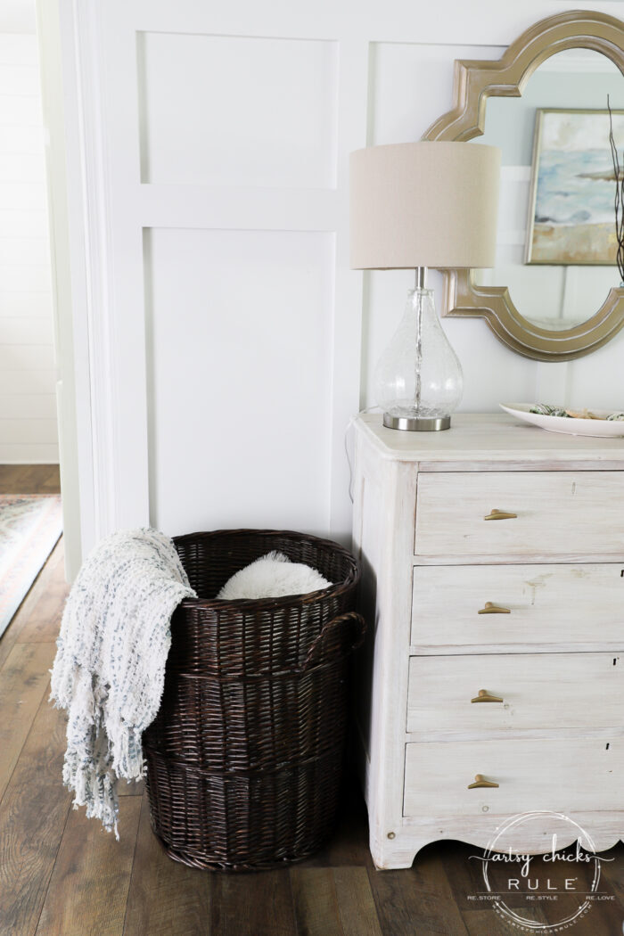 Dark brown tall basket filled with blankets and pillows