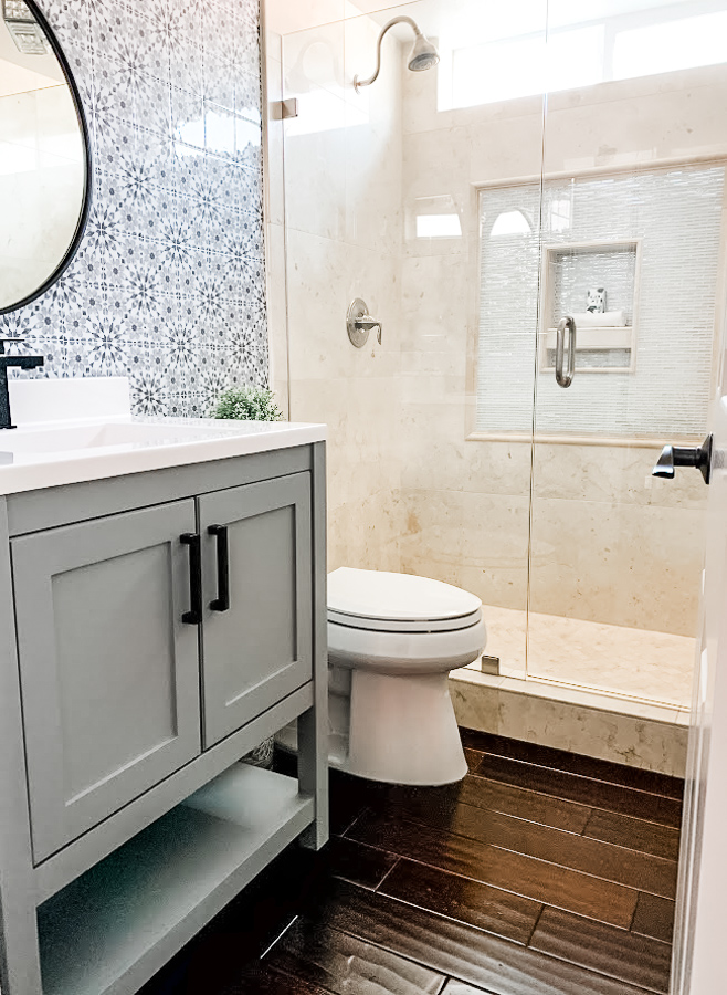 gray bath cabinet, wood floors and patterned decorative wall tiles