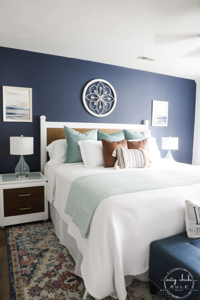 finished full shot of bedroom with white bed, colorful rug, white and woo headboard