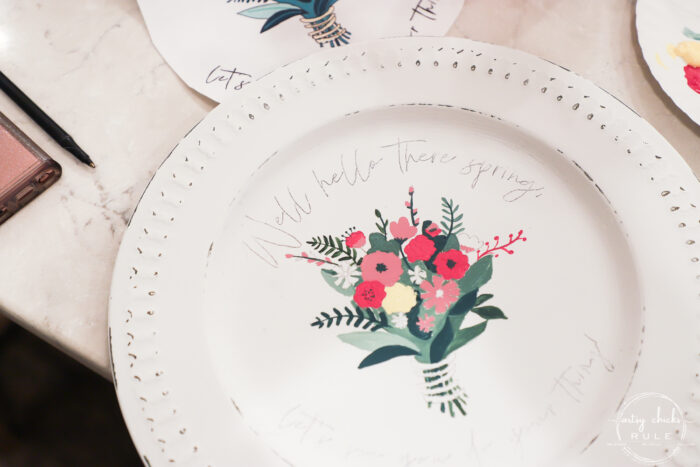 white charger plate with pink flowers, green leaves and a yellow flower