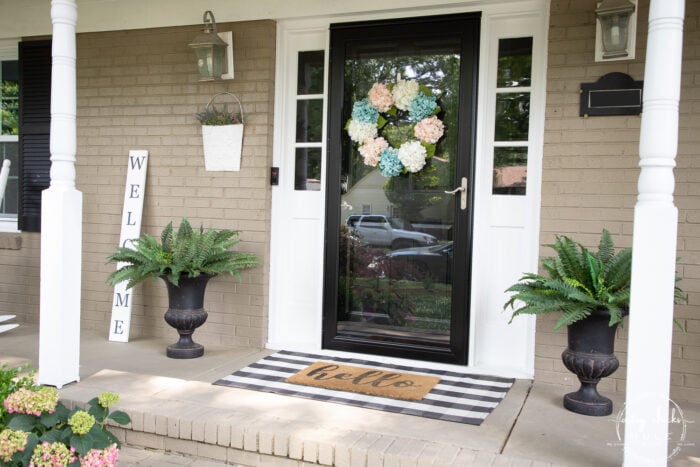 front door with white columns and black and white plaid mat