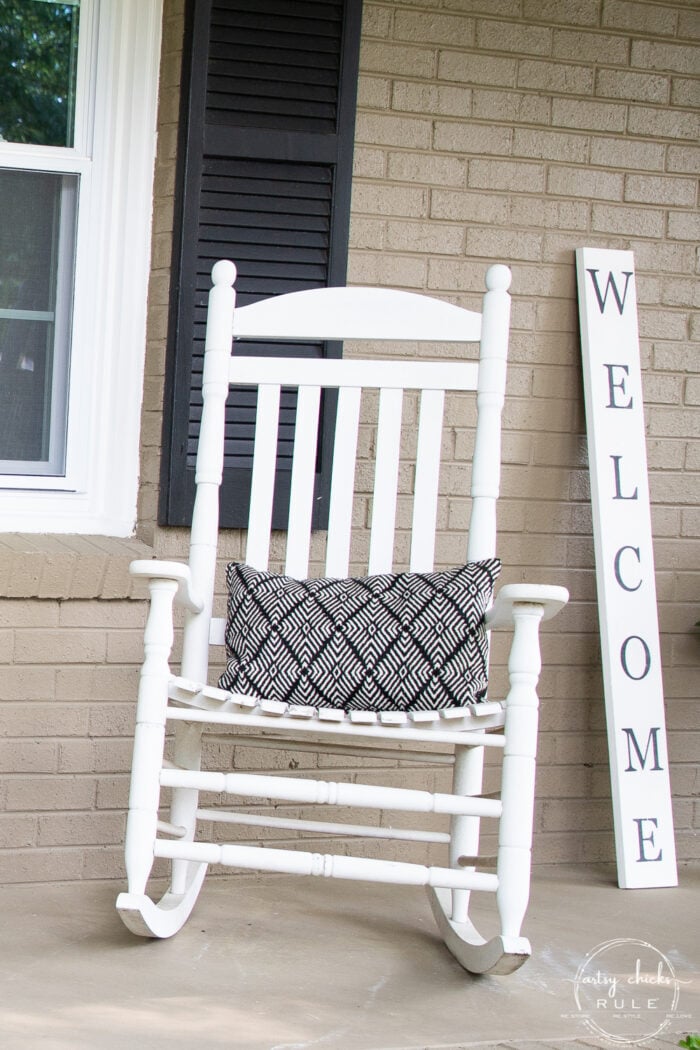 white rocker with black and white pillow and welcome sign