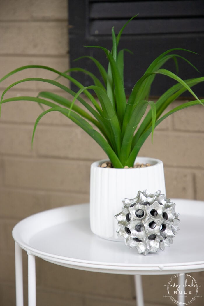 white jar, green plant and silver ball