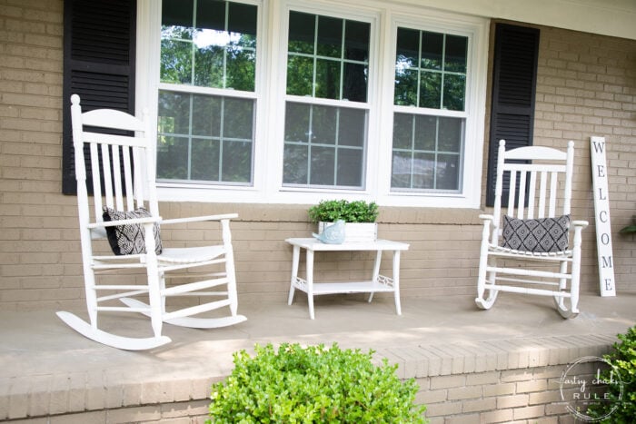 2 white rockers with white table tan house black shutters