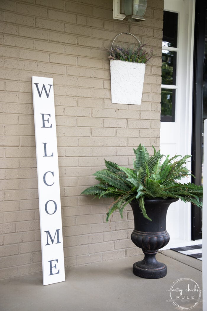 tall welcome sign with green fern