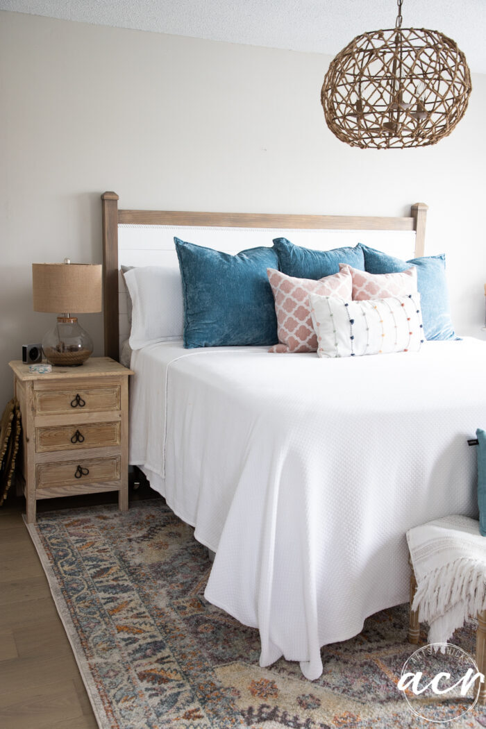 colorful pillows on white bed on colorful rug