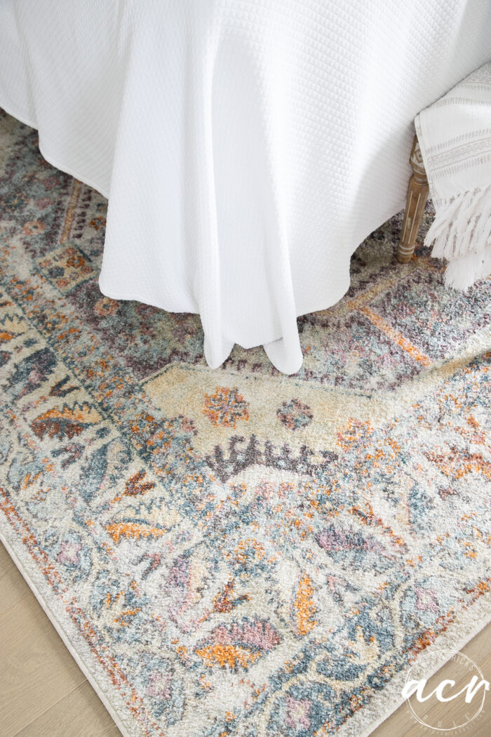 white bedding and colorful rug