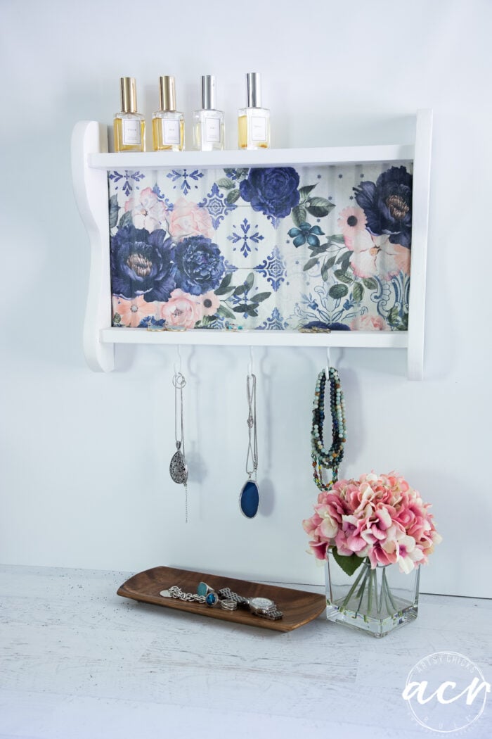 white shelf with blue flowers styled with perfume bottles and jewelry