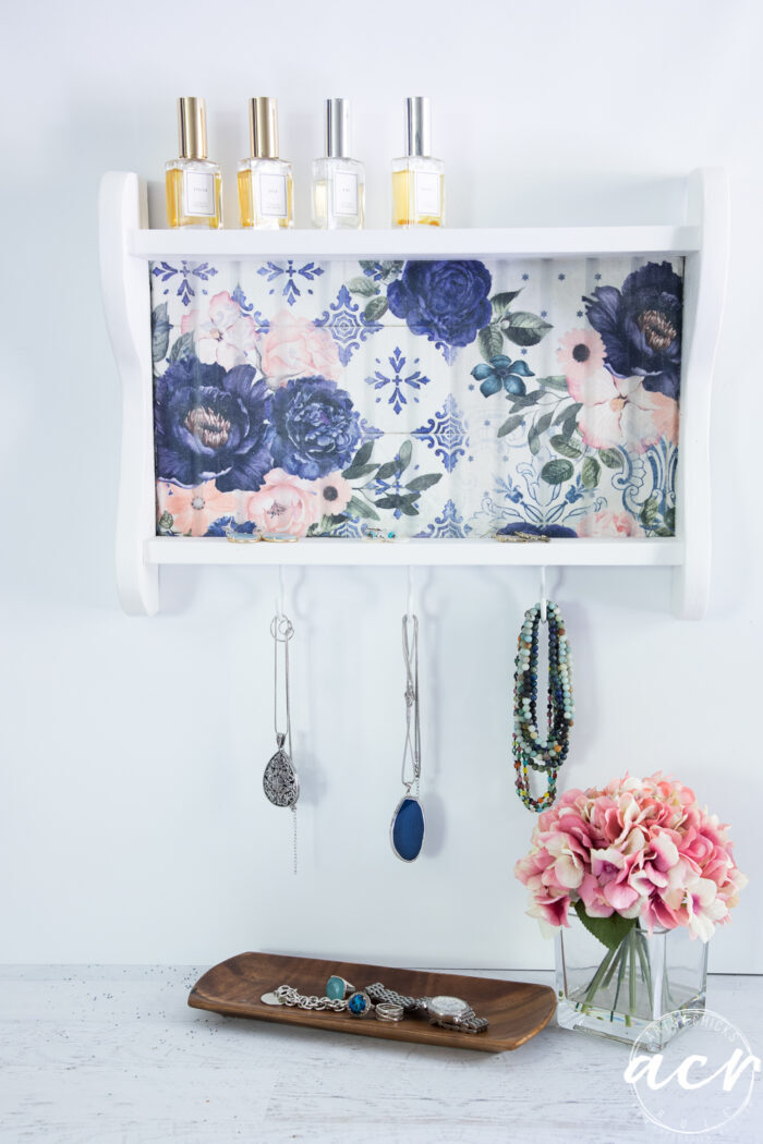 blue floral shelf hanging on wall with jewelry