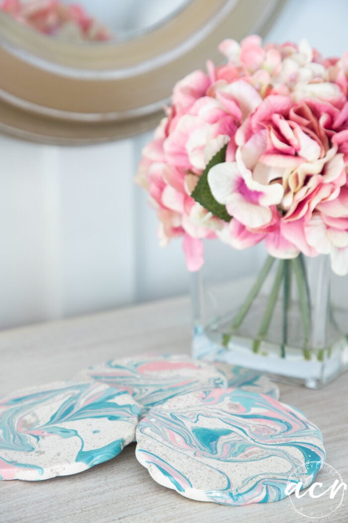 pink flowers in vase with blue and pink coasters