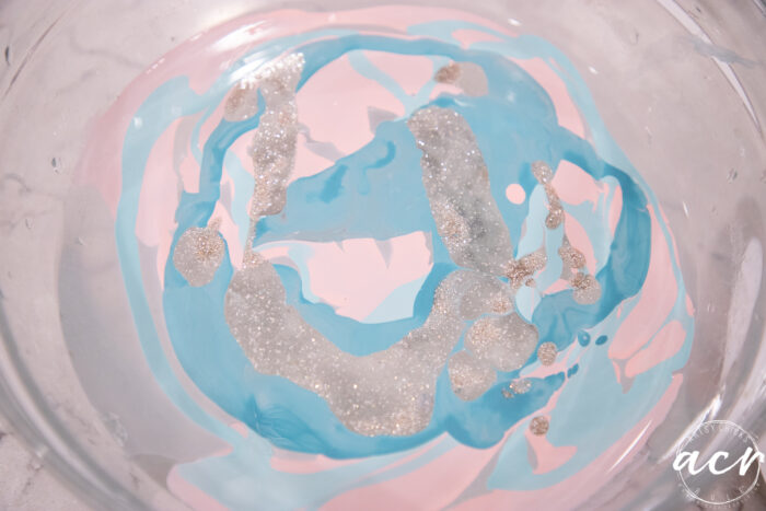 pink blue and sparkled nail polish floating in bowl