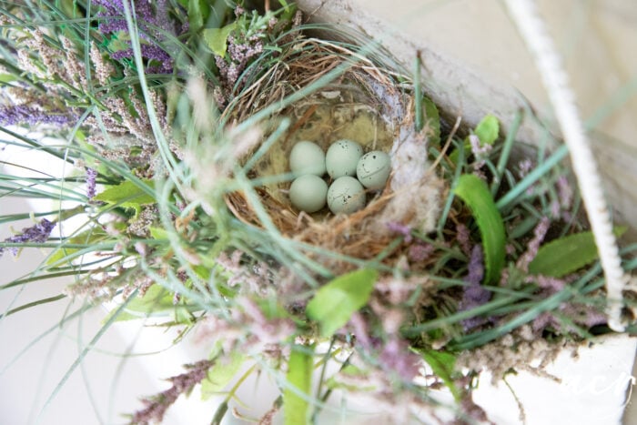 top view of hanging metal basket with bird's nest and baby blue speckled eggs