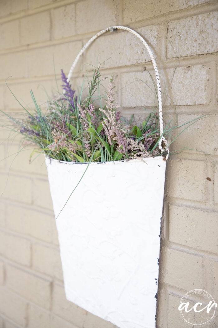 white metal half basket on brick wall with flowers in side