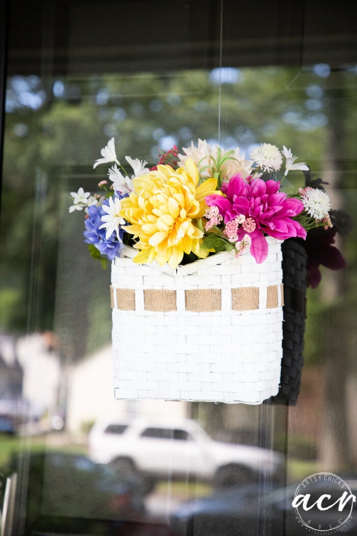 front view of basket with burlap ribbon and colorful flowers