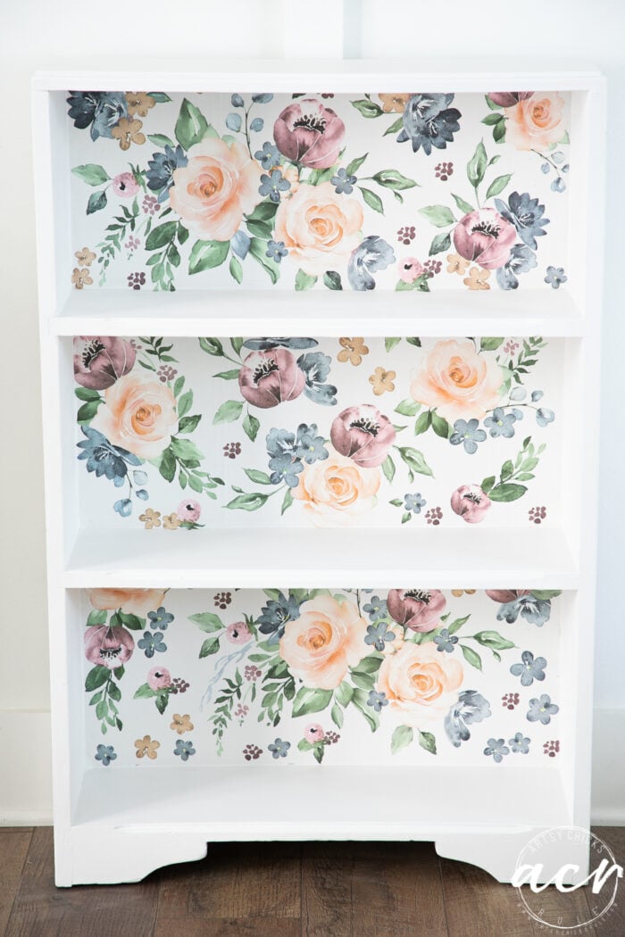 small white bookcase with colorful floral backing