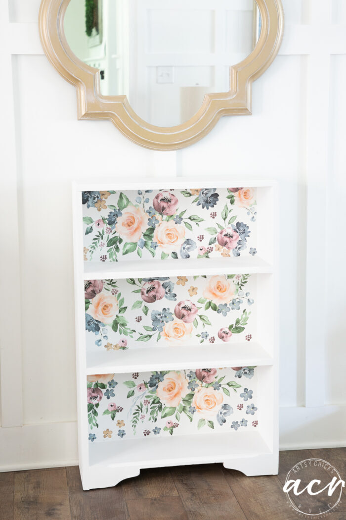 floral and white bookcase with white wall and gold mirror