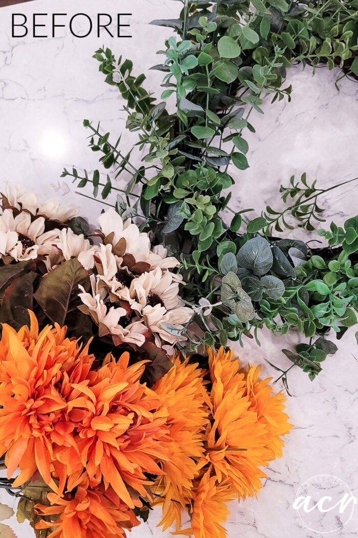 green wreath before with bunches of orange and cream flowers beside it