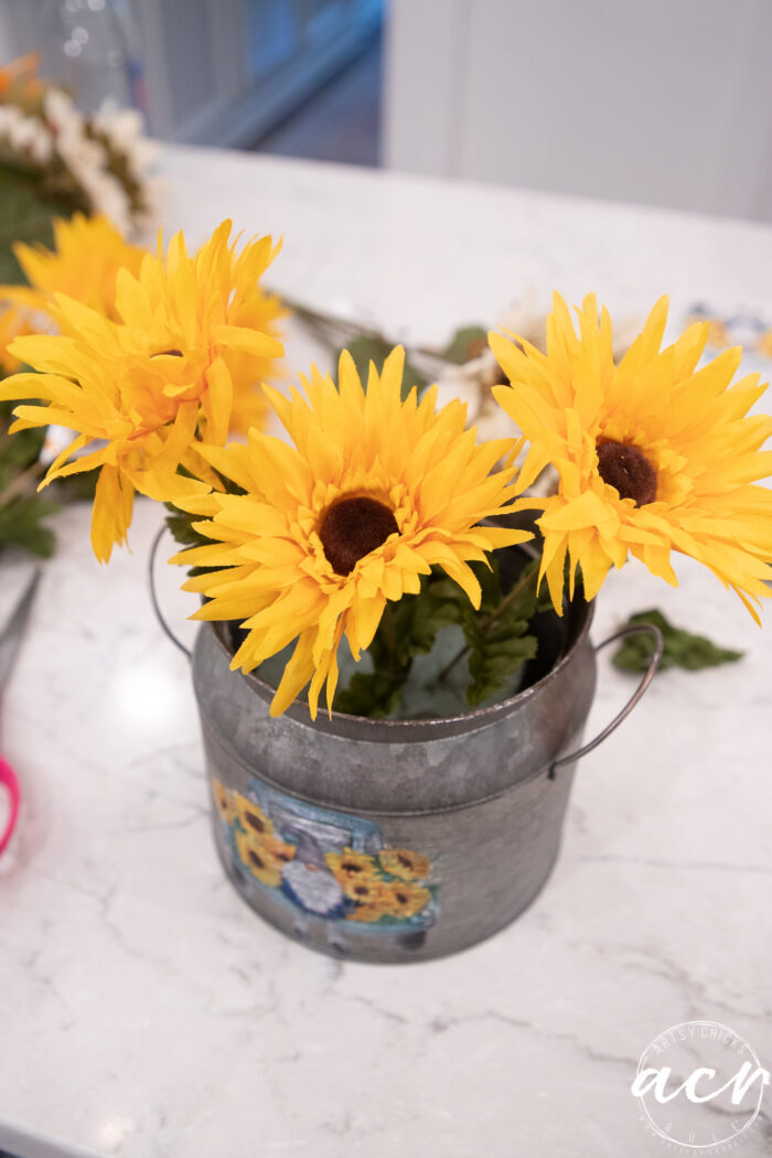 adding the yellow sunflowers to the tin