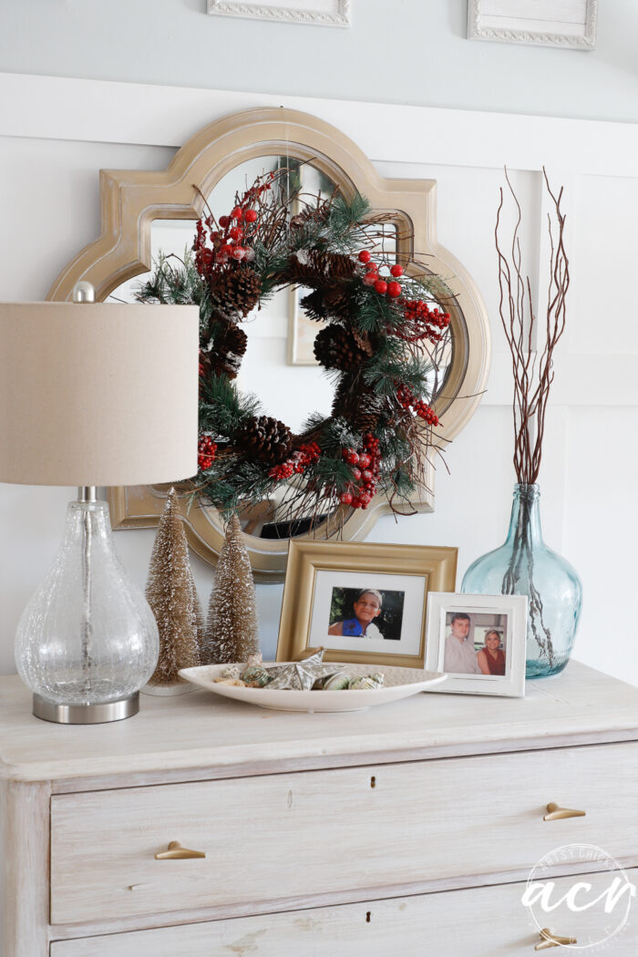 gold mirror with Christmas wreath hanging on it 